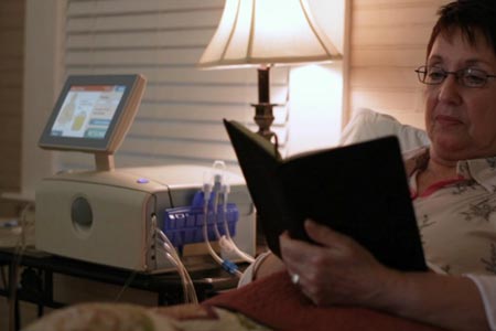 Woman in bed reading while receiving APD