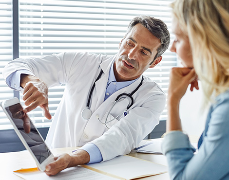 A doctor holding a tablet and explaining a woman something on the screen